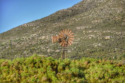 Windmill on grassy field against mountain