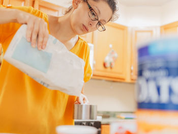 Young millennial mother at home in the kitchen preparing ingredients for apple crisp