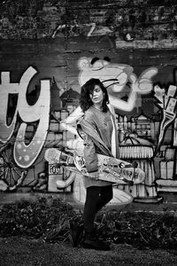 Portrait of young woman standing on graffiti