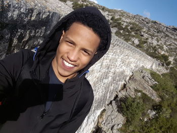 Portrait of smiling young man standing on mountain