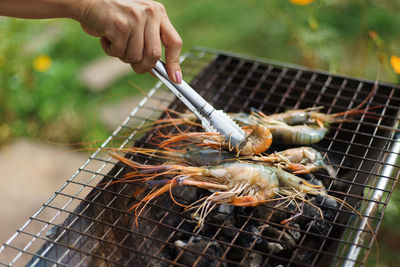 Close-up of hand grilling prawn