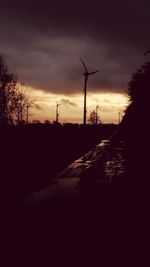 Silhouette of windmills on landscape against sunset sky