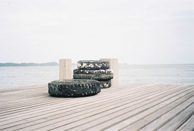 Tire on pier at sea against sky