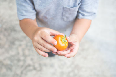 Cropped image of child showing tomato