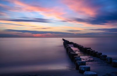 Pier over sea against sky at sunset