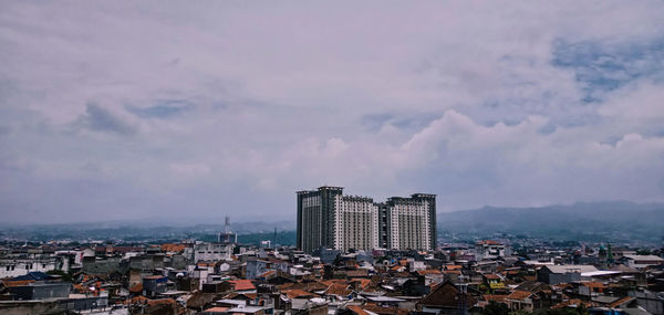 Buildings in city against cloudy sky