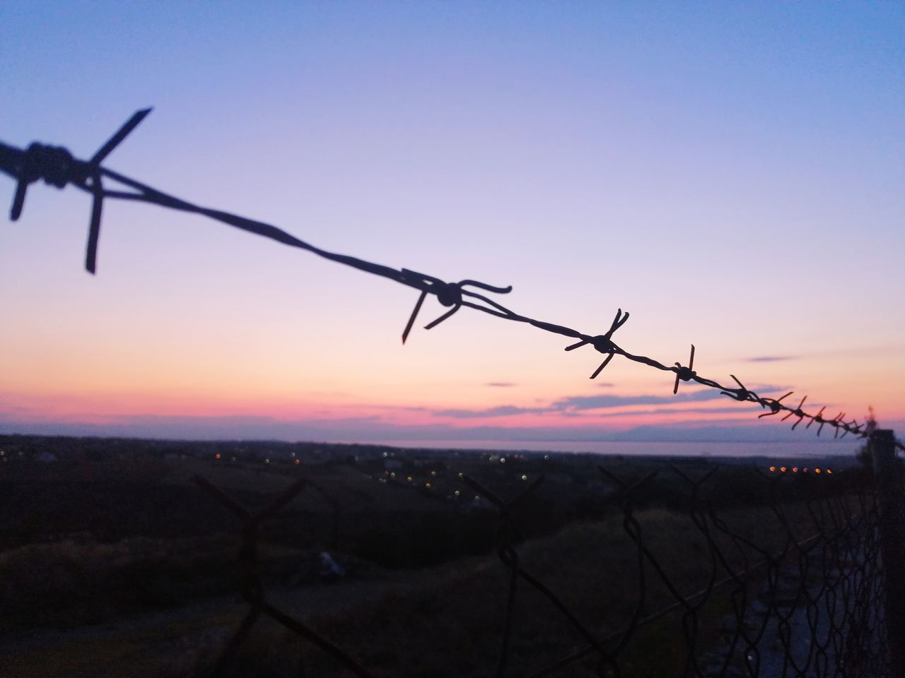 BARBED WIRE AGAINST SKY DURING SUNSET