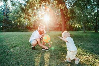 Fathers day. father playing ball with toddler baby boy outdoor. 