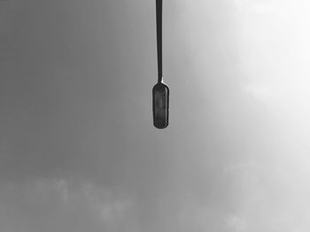 Low angle view of electric lamp hanging against sky