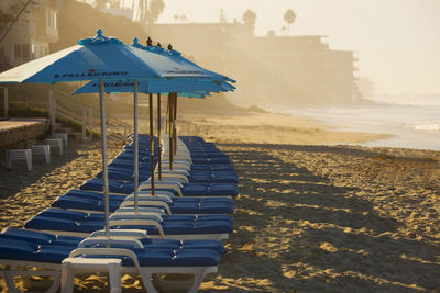 Deck chairs on beach against sky