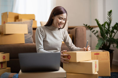 Smiling entrepreneur packing packages at store