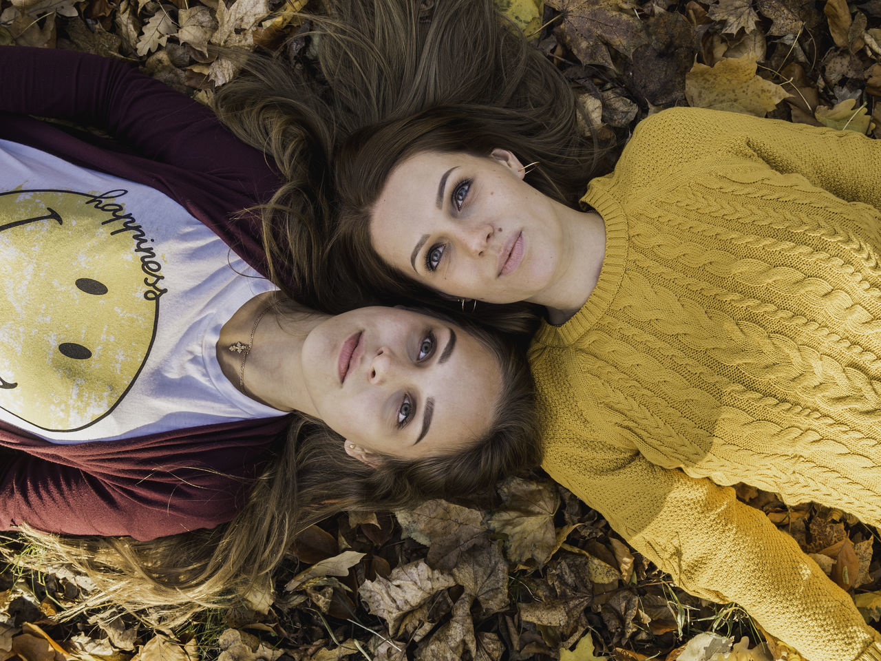 HIGH ANGLE VIEW PORTRAIT OF SMILING GIRL LYING DOWN OUTDOORS