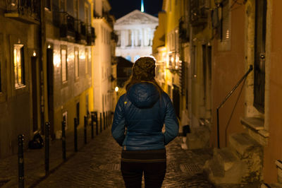 Rear view of man in illuminated city at night