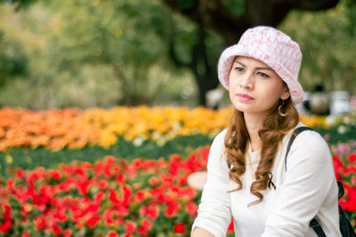 Portrait of a beautiful young woman standing by flower plants