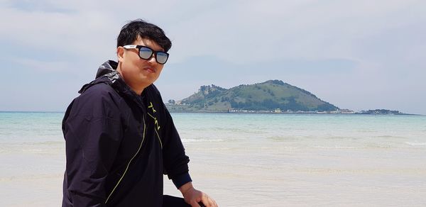 Portrait of man at beach against sky