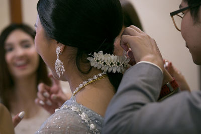 Close-up of groom wearing flowers on bride hair