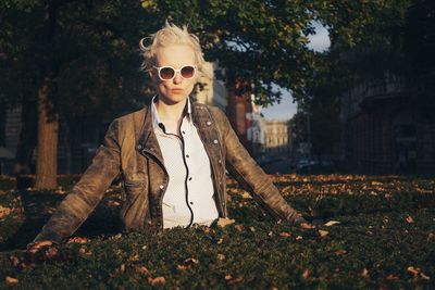 Portrait of young woman wearing sunglasses standing against trees