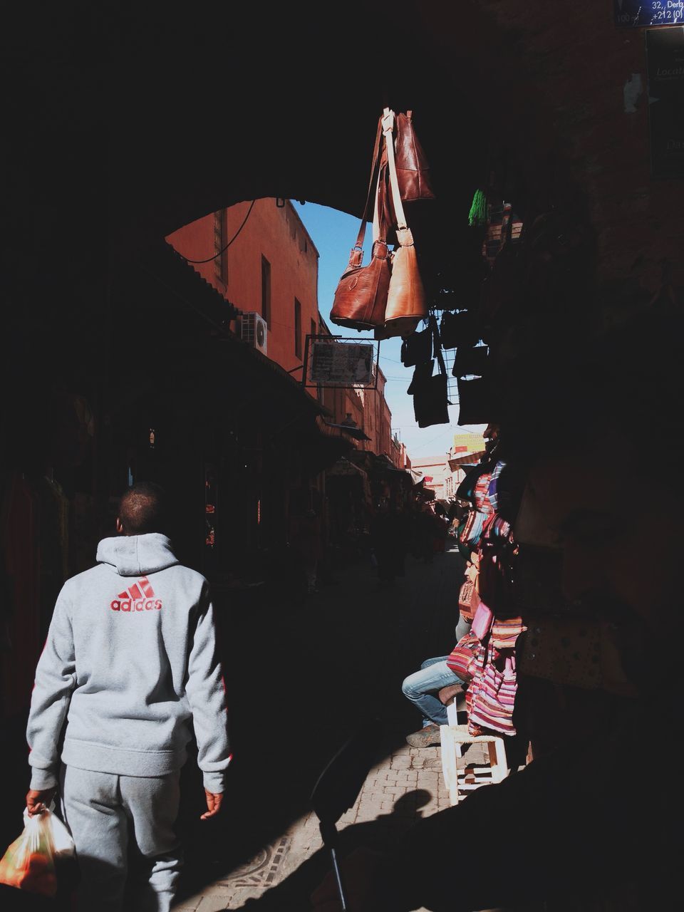 REAR VIEW OF WOMAN STANDING ON STREET MARKET