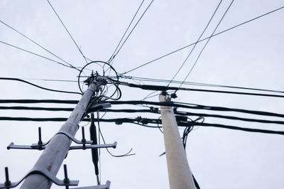 Powerline posts with electrical wires and capacitors above old roofs. electricity transmission line.