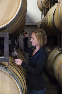Side view of woman examining wine at cellar