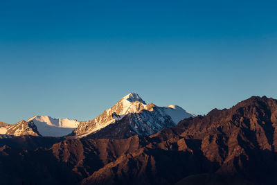 Scenic view of snowcapped mountains against clear blue sky