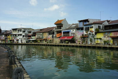 Buildings by lake against sky