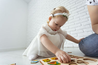 Portrait of cute baby girl sitting on floor at home