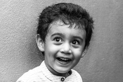 Close-up of cheerful boy against wall
