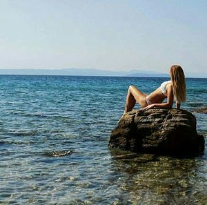 Woman relaxing in sea against sky