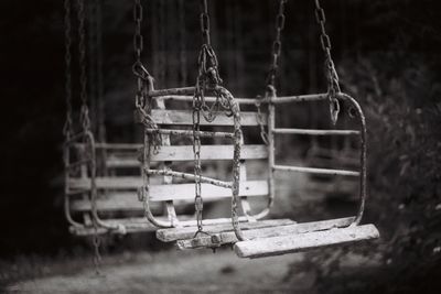 Close-up of weathered swings hanging in playground