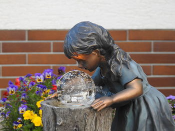 Side view of a child figure holding sculpture