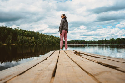 Man standing on pier by lake against sky