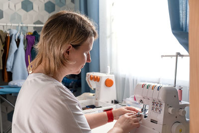 Real middle aged woman tailor sewing clothes using a sewing machine. process of sewing clothes.