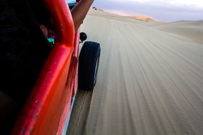 Low section of person on car against sky