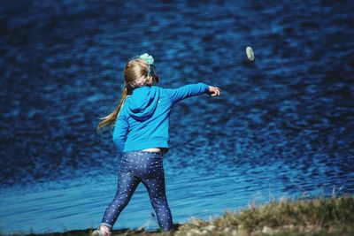 Rear view of girl throwing pebble