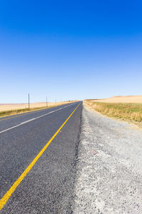 Road against clear blue sky