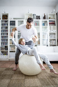 Father and son with fitness ball at home