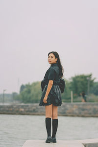 Damsel in uniform by a lake on a cloudy day