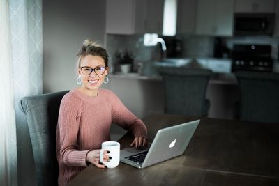 Woman using phone while sitting on table