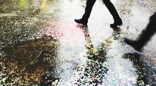 Low section of men walking on wet street during monsoon