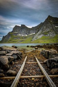 Railroad tracks by mountain against sky