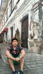 Full length portrait of smiling young man in city buildings