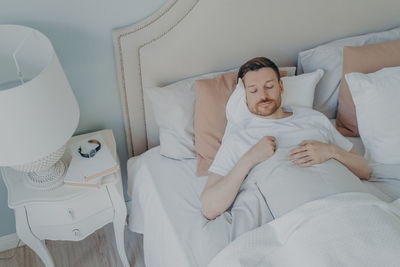 High angle view of man sleeping on bed at home