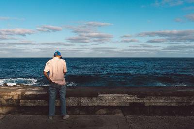 Rear view of man standing by sea against sky