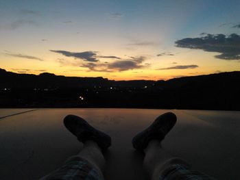 Low section of man against sky during sunset