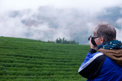 Rear view of boy using mobile phone on field