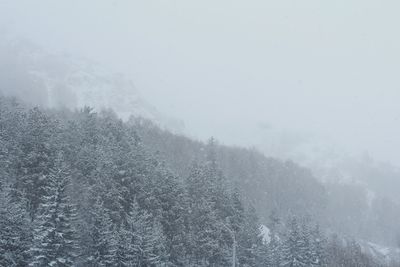 Snow covered landscape against sky during foggy weather