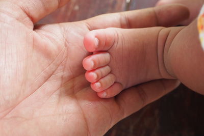 Cropped hand of parent holding baby feet
