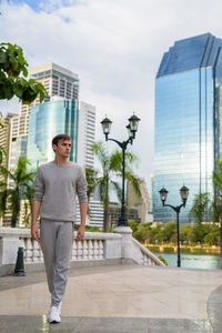 Portrait of young man standing against modern buildings in city