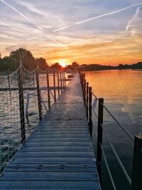 Pier over lake against sky during sunset